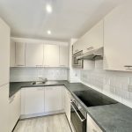 Modern white kitchen with sleek cabinets and appliances.