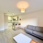 Modern flat with sofa, table, and kitchen area.