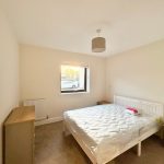 Minimalist bedroom with bed and wooden furniture.