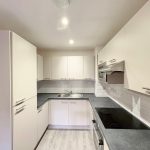 Modern kitchen with white cabinets and dark countertop.