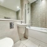 Modern bathroom with tiled walls and bathtub.