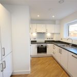 Modern kitchen with white cabinets and wooden floor.