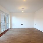 Spacious empty room with wooden floor and windows.