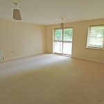 Spacious empty living room with carpet and windows.