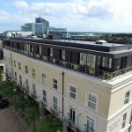 Modern building with rooftop terrace and glass windows.