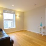 Bright living room with leather sofa and wooden flooring.