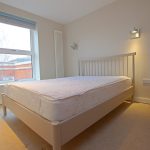 Bright bedroom with double bed and window view.