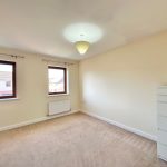 Empty room with two windows and chest of drawers.