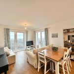 Bright living room with dining table and balcony view.