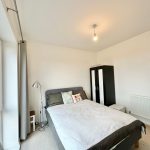 Bright bedroom with bed, lamp, and wardrobe.