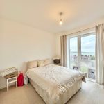 Bright minimalist bedroom with double bed and window.