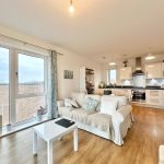 Modern open-plan living area with kitchen and sofas.