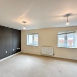 Spacious lounge with carpet and two windows.