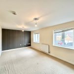 Spacious empty room with large windows and neutral decor.