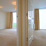 Empty modern apartment with large windows and neutral decor.