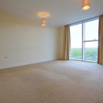 Spacious empty room with large window and curtains.