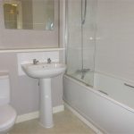 Modern bathroom with white fixtures and bathtub.