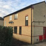 Two-storey brick house with red door and windows.