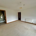 Empty room with carpet and open bathroom door.