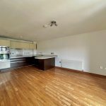 Modern empty kitchen with wooden flooring.