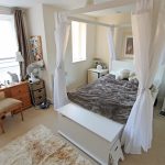 Cosy bedroom with four-poster bed and dressing table.