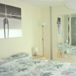 Modern bedroom with abstract artwork and wavy mirrors.
