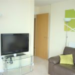 Modern living room with TV and brown sofa.