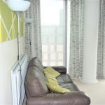 Modern living room with sofa and tall windows.