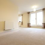 Spacious living room with cream carpets and large windows.