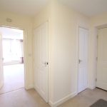 Bright corridor with four white doors.