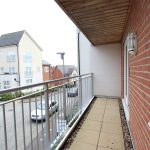 Modern balcony overlooking residential street and houses.
