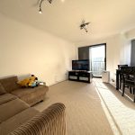 Bright living room with sofa, TV, and dining area.