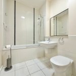 Modern white bathroom with a bathtub and mirror.