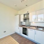 Modern kitchen with white cabinets and stainless appliances.