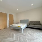 Modern bedroom with grey sofa and bed.