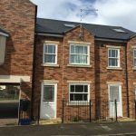 Modern UK brick townhouse exterior with driveways.