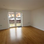 Empty room with wooden floor and patio doors.