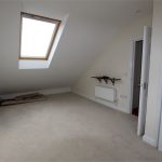 Spacious room with skylight and white walls.