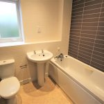 Modern bathroom with white tiles and fixtures.