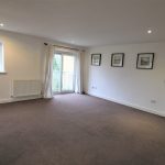 Spacious empty room with carpet and windows.