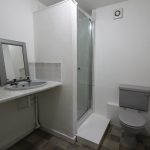 Compact bathroom with sink, shower, toilet.
