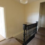 Carpeted landing with black banister and doorways