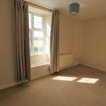 Empty room with window and beige curtains.
