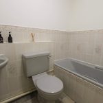 Small tiled bathroom with toilet and bathtub.
