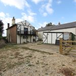 Traditional English farmhouse with courtyard and gate.