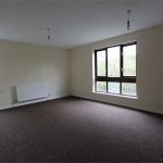 Empty room with large windows and carpet flooring.