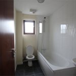 Modern bathroom with bathtub and tiled walls.