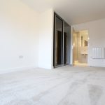 Empty room with beige carpet and en-suite bathroom.