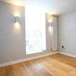 Empty room with wooden floor and large window.