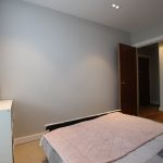 Minimalist bedroom with white dresser and open door.